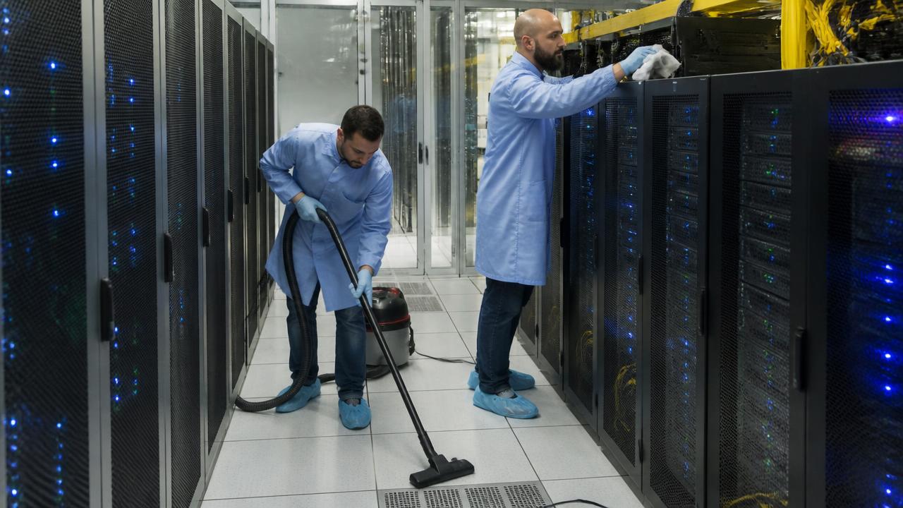 ESD-certified technicians HEPA vacuuming the raised floor and wiping rack tops in a colocation data center white space